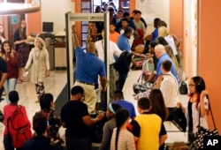 FILE - In this Sept. 6, 2016, photo, students at William Hackett Middle School have their bags checked and pass through metal detectors on the first day of school in Albany, New York.