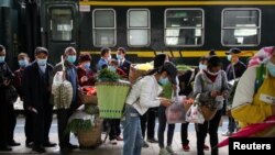 A pesar del levantamiento de muchas restricciones por el coronavirus en China, los viajeros tienen que presentar códigos de salud a las autoridades, como en esta estación de la procinvia de Guizhou el 16 de abril de 2020.