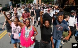 Demonstrators against racism march along city streets as they mark the anniversary of last year's Unite the Right rally in Charlottesville, Va., Sunday, Aug. 12, 2018.