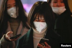 Women wearing face masks wait for the bus on an extremely polluted day with red alert issued, in Langfang, Hebei province, China, Dec. 19, 2016.