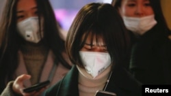 Women wearing face masks wait for the bus on an extremely polluted day with red alert issued, in Langfang, Hebei province, China, Dec. 19, 2016.