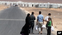 A Syrian refugee family walks towards the new Syrian camp of Azraq, which stretches for 15 kilometers, and lies about 100 kilometers from the Syrian border in Jordan, Wednesday, April 30, 2014.