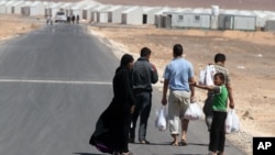Satu keluarga pengungsi Suriah berjalan menuju kamp pengungsi Azraq yang baru dibuka di Yordania dekat perbatasan Suriah (30/4). 