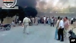 People gather in a street in Hama as smoke rises in the background in this video image posted on a social media website on August 2, 2011 (the authenticity of the video from which this image was taken cannot be independently verified)