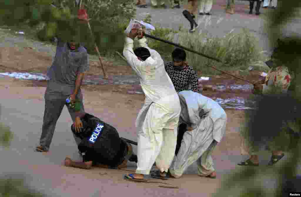 Anti-government protesters beat a riot policeman after clashes during the Revolution March in Islamabad, Pakistan.