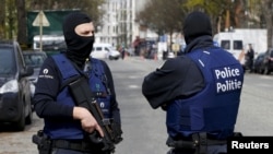 FILE - Belgium police officers secure an area during a police operation in Etterbeek, near Brussels, Belgium, April 9, 2016. 