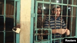 A Palestinian inmate stands behind the bars of a Hamas-run jail in Gaza City after prayers during the holy month of Ramadan, July 23, 2012.