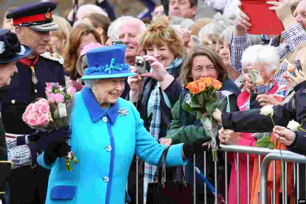 Ratu Inggris Elizabeth II menyapa simpatisannya sebelum ia meresmikan plakat peringatan di stasiun kereta api Newtongrange di desa Midlothian sehari sebelum ia menjadi penguasa kerajaan Inggris terlama.