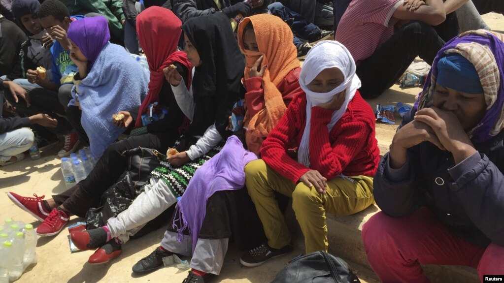 FILE - Migrants who attempted to sail to Europe sit on the shore after their boat was intercepted at sea by the Libyan coast guard in Khoms, Libya, May 6, 2015.