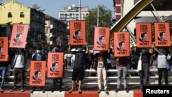 FILE - Demonstrators hold up placards depicting deposed Myanmar leader Aung San Suu Kyi during a protest against the Feb. 1, 2021, military coup in the country, in Yangon, Myanmar, Feb. 17, 2021. 