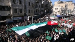 Jordanian protesters hold a giant national flag, as they march during a protest demanding the resignation of the prime minister and his government over price increases and inflation, in Amman, 21 Jan 2011