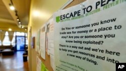 FILE - A poster on the wall of a drop-in center for victims of sex trafficking in SeaTac, Washington, refers victims to a similar program at different location, Feb. 27, 2017.