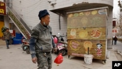 Seorang pekerja berjalan melewati kios jalanan yang tutup di Aksu, Daerah Otonomi Uyghur Xinjiang, China barat, 18 Maret 2021. (AP Photo/Ng Han Guan)
