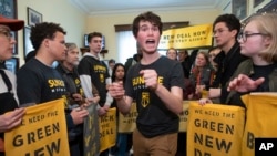 Jeremy Ornstein of Watertown, Mass., center, cheers on fellow environmental activists as they occupy the office of Rep. Steny Hoyer, D-Md., the incoming majority leader on Capitol Hill in Washington, Dec. 10, 2018. 