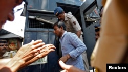 Policemen escort one of the four men convicted of raping a photojournalist outside a jail in Mumbai, March 20, 2014. 