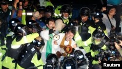 FILE - People scuffle with riot police during a protest opposing the deployment of a Terminal High Altitude Area Defense (THAAD) system in Seongju, South Korea, Sept. 7, 2017.