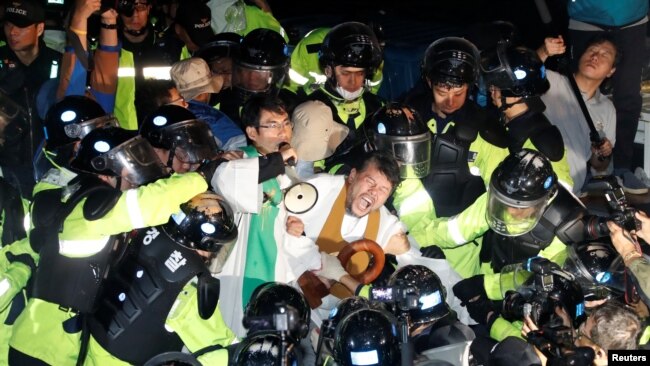 FILE - People scuffle with riot police during a protest opposing the deployment of a Terminal High Altitude Area Defense (THAAD) system in Seongju, South Korea, Sept. 7, 2017.