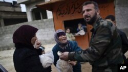A woman asks a Free Syrian Army fighter to sell her bread, in Maaret Misreen, near Idlib, Syria, December 13, 2012.