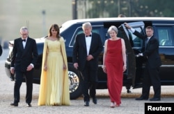 U.S. President Donald Trump and first lady Melania Trump are met by British Prime Minister Theresa May and her husband, Philip, at Blenheim Palace, where they are attending a dinner with other specially invited guests and business leaders, near Oxford, July 12, 2018.