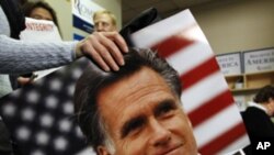 A supporter of U.S. Republican presidential candidate and former Massachusetts Governor Mitt Romney carries a photo of Romney past a campaign worker calling potential voters in Greenville, South Carolina, January 21, 2012.