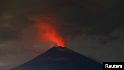 Lava, inside the crater of Mount Agung, reflects off the volcano's ash and clouds, while it erupts, as seen from Amed, Karangasem Regency, Bali, Indonesia, Nov. 30, 2017. 