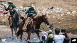 US Customs and Border Protection mounted officers attempt to contain migrants as they cross the Rio Grande from Ciudad Acuña, Mexico, into Del Rio, Texas, Sept. 19, 2021.