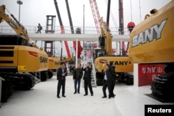 FILE - People visit heavy machinerys of Sany at Bauma China 2016, The 8th International Trade Fair for Construction Machinery in Shanghai, China, Nov. 22, 2016.