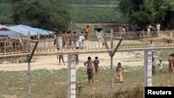 Rohingya people who fled from their towns after the violence in the state of Rakhine, are seen behind a fence on the border line outside Maungdaw, Myanmar, March 31, 2018.