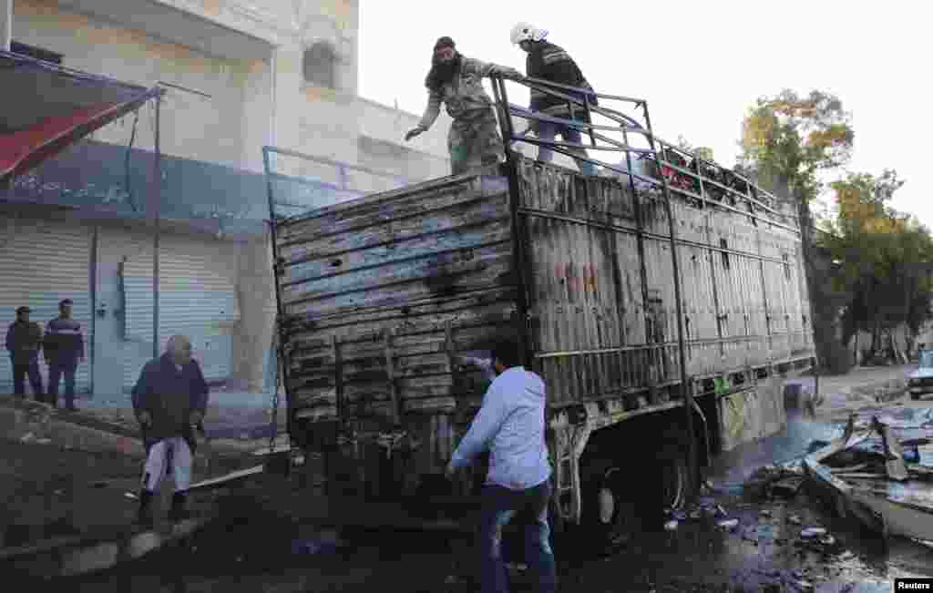 Civil defense members and civilians extinguish the fire from a burning truck after what activists said were explosive barrels thrown by forces loyal to President Bashar al-Assad, al-Inzarat district, Aleppo, Feb. 18, 2014.