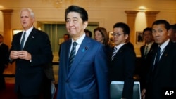 Japanese Prime Minister Shinzo Abe, center, tours the John F. Kennedy Presidential Library in Boston, with Edwin Schlossberg, left, and Caroline Kennedy, background center, Sunday, April 26, 2015.