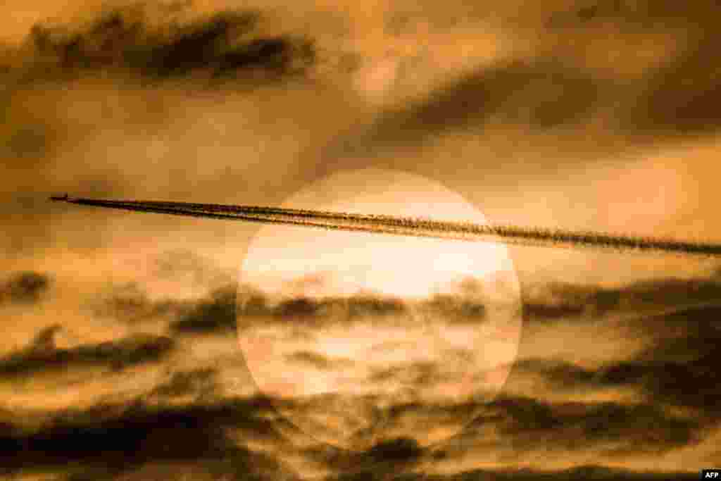 A passenger plane flies past the sun in Yangon, Myanmar.