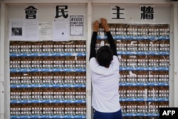 FILE - A student union member removes adjusts posters to make space for other students to display notices at the Chinese University of Hong Kong in Hong Kong, September 7, 2017.