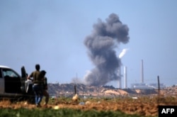 Palestinians look at smoke billowing from the site of an Israeli air strike on a Hamas' military site in Beit Lahia near the border between Israel and the Gaza Strip, east of Jabalia on May 14, 2018.