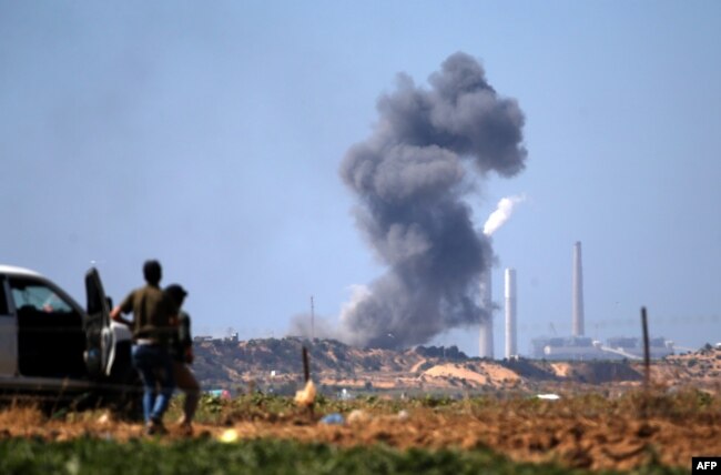 Palestinians look at smoke billowing from the site of an Israeli air strike on a Hamas' military site in Beit Lahia near the border between Israel and the Gaza Strip, east of Jabalia on May 14, 2018.