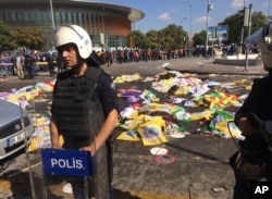 Bodies of victims are covered with flags and banners as a police officer secure the area after an explosion in Ankara, Turkey, Oct. 10, 2015.