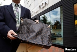 FILE - A fake LVMH handbag purchased and shipped from a China-based website is displayed for a photographer, outside a Louis Vuitton store in Chevy Chase, Maryland.