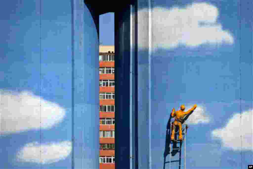A model of a worker painting blue sky and white clouds is installed on the exterior of a building of a power plant in Beijing, China, Thursday, Oct. 14, 2010. China and the U.S. are working together on cutting greenhouse gas emissions despite the deadlock