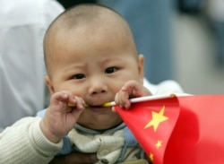 Seorang bayi memegang bendera nasional di Lapangan Tiananmen di ibu kota China, Beijing. (Foto: Reuters)