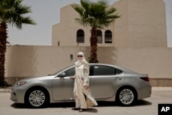 In this Sunday, June 24, 2018 photo, Ammal Farahat, who has signed up to be a driver for Careem, a regional ride-hailing service that is a competitor to Uber, poses for a photograph next to her car on a street in Riyadh, Saudi Arabia.