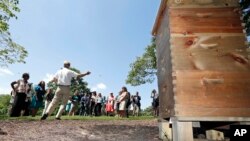 Larry Marling of Eco HoneyBees in Falls Church, Va., left, speaks as Karen Pence, the wife of Vice President Mike Pence; Agriculture Secretary Sonny Perdue with his wife, Mary Perdue; and others listen to his description of the new beehive placed at the vice president's residence in Washington, June 6, 2017.