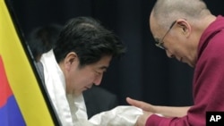 Tibetan spiritual leader the Dalai Lama, right, gives a white Tibetan scarf to Japan's main opposition Liberal Democratic Party President Shinzo Abe during a seminar held by Japanese Diet members in Tokyo, Tuesday, Nov. 13, 2012. (AP Photo/Itsuo Inouye)