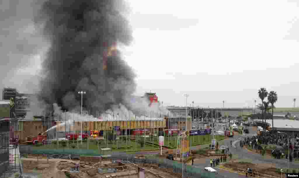 Members of the public stand in front of the burning Jomo Kenyatta International Airport, Nairobi, August 7, 2013.