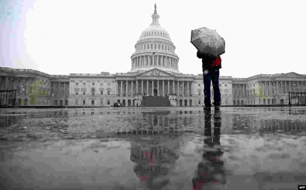 2013年3月6日，华盛顿雨雪交加，一位游客在美国国会山附近打伞遮蔽雨雪。