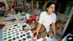 FILE - A woman from Myanmar sells rubies and other semi-precious stones at a market in Mae Sot, Thailand, Oct. 21, 2007. A U.S. a ban on the import of jadeite and rubies, one of Myanmar's most profitable industries, remains in place.