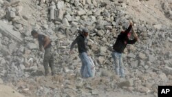 FILE - Palestinian workers salvage metal to sell and collect rubble from destroyed buildings to make recycled concrete bricks to be used in the reconstruction of war damaged buildings, east of Gaza City, Nov. 24, 2021.