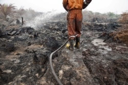 Seorang petugas pemadam kebakaran dari Badan Penanggulangan Bencana Daerah mencoba memadamkan kebakaran lahan gambut di perkebunan kelapa sawit di Pelalawan, Provinsi Riau, 26 September 2015. (Foto: Antara/FB Anggoro via REUTERS)