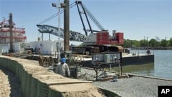 A worker from ABL Fabricators, L.L.C. walks along a temporary levee system set up along the Bayou Boeuf waterway in Amelia, Louisiana, May 17, 2011