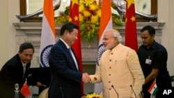 Presiden China Xi Jinping menjabat tangan PM India Narendra Modi (kanan) seusai penandatanganan kesepakatan di New Delhi, India (18/9).