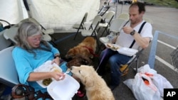 Evacuees Donna Herzog and her husband Richard Herzog, with their five dogs, eat food served by volunteers, in the aftermath of Tropical Storm Harvey, in a staging area as they wait for buses to go to evacuation shelters in Vidor, Texas, Sept. 1, 2017.