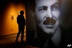 A museum visitor, left, walks past a photograph of Ernest Hemingway in the exhibit: "Ernest Hemingway: Between Two Wars" at the John F. Kennedy Presidential Library and Museum in Boston, April 12, 2016.